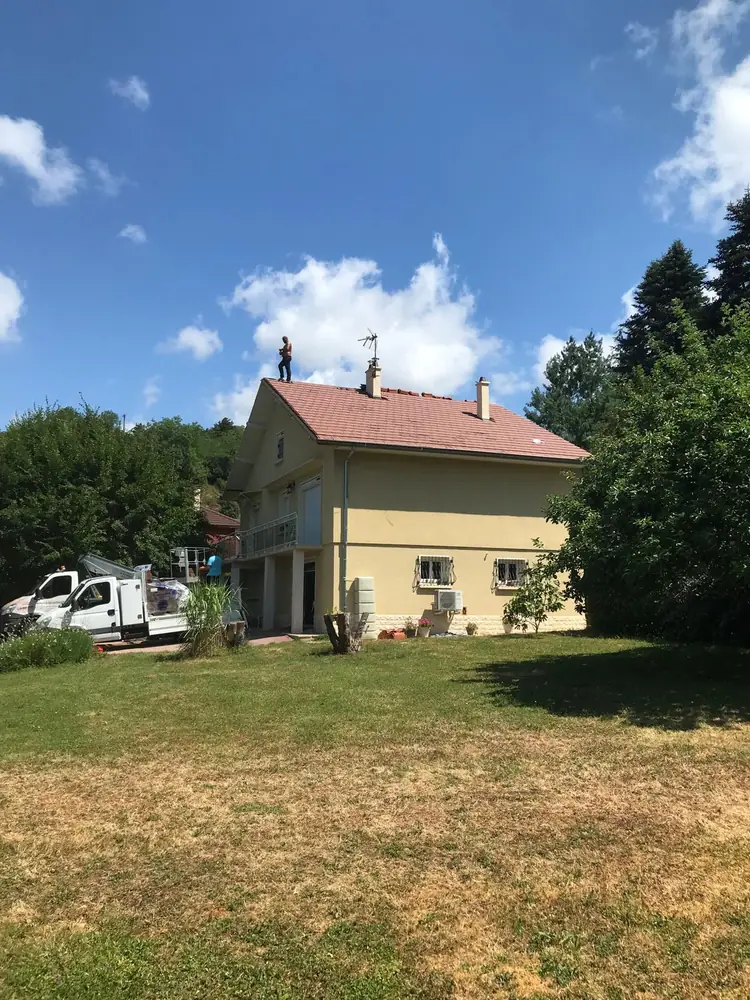 Maison avec toiture en cours de rénovation, couvreur sur le toit et nacelle